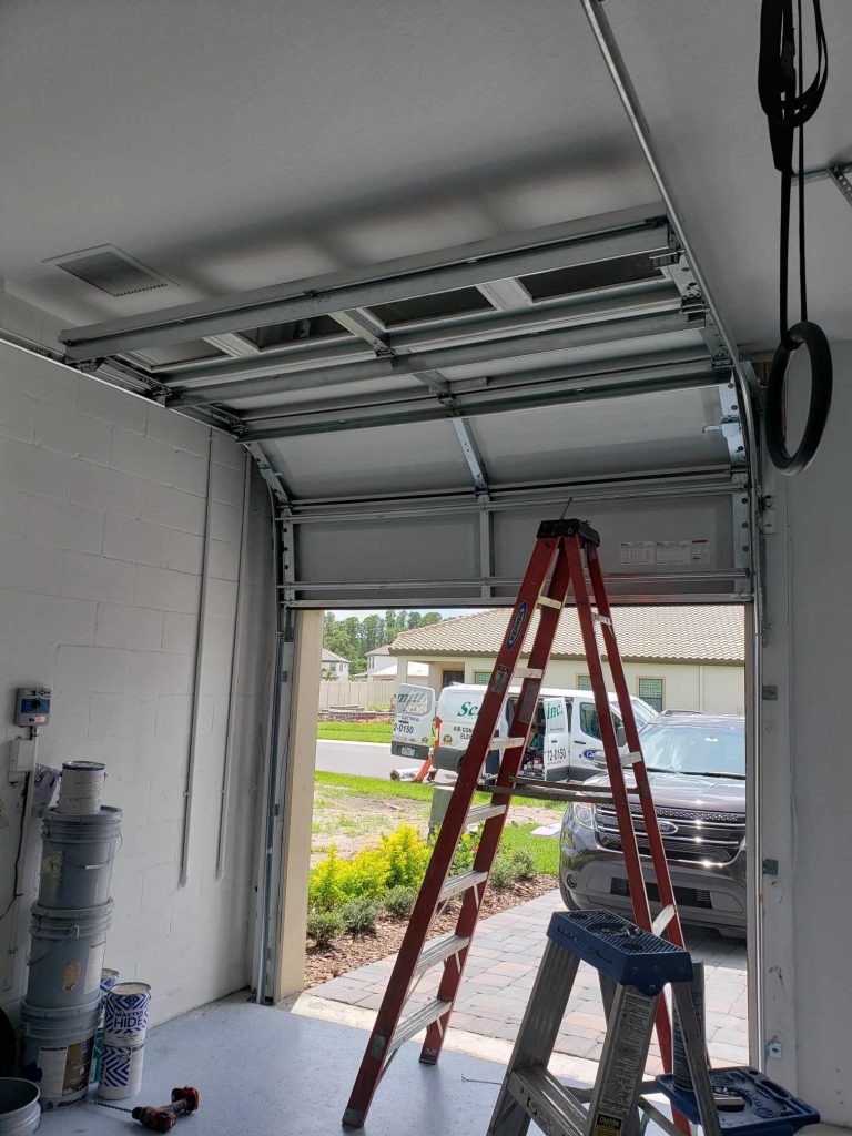 A garage door raised on its tracks during a Trinity job, seen from inside the garage