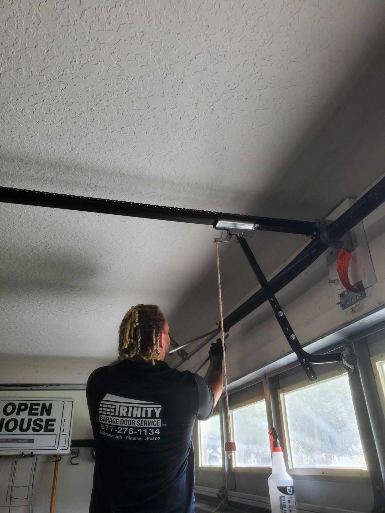 Trinity technician working on a garage door at dusk in Palm Harbor