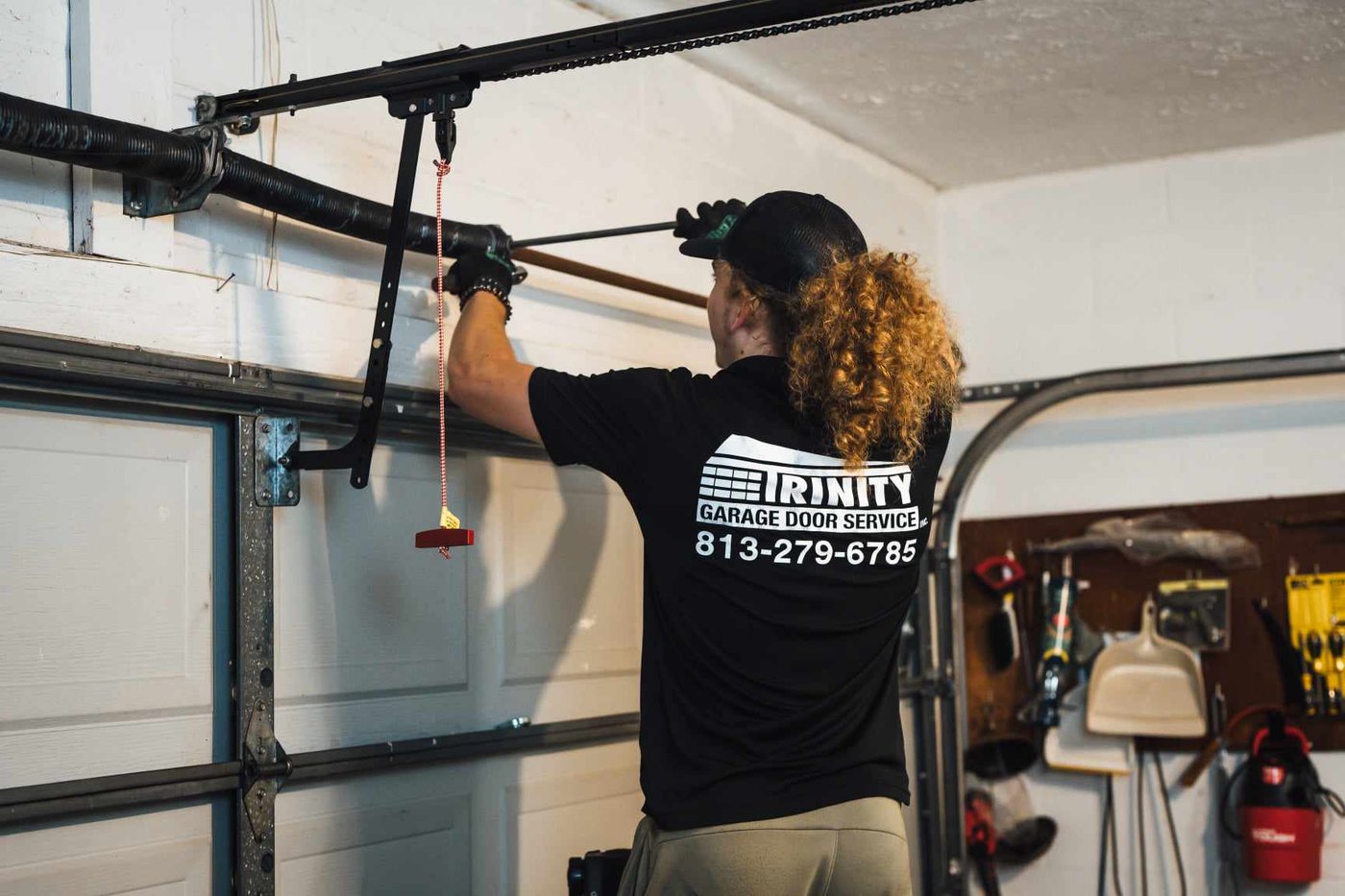 A Trinity technician working on a garage door torsion spring shaft